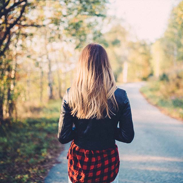 Ryggen på en tjej med svart jacka och rutig kjol